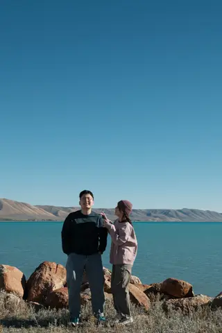 两人在蓝色湖水与群山前合影